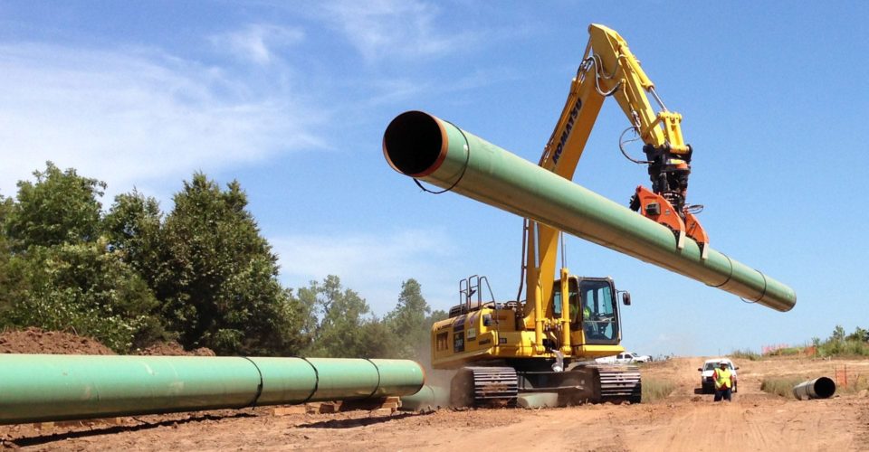 The DECKHAND® system in action! In this image a DECKHAND® is attached to an excavator. Outfitted with Pipe Arms, the DECKHAND® makes quick work of handling pipe around a civil construction job site.