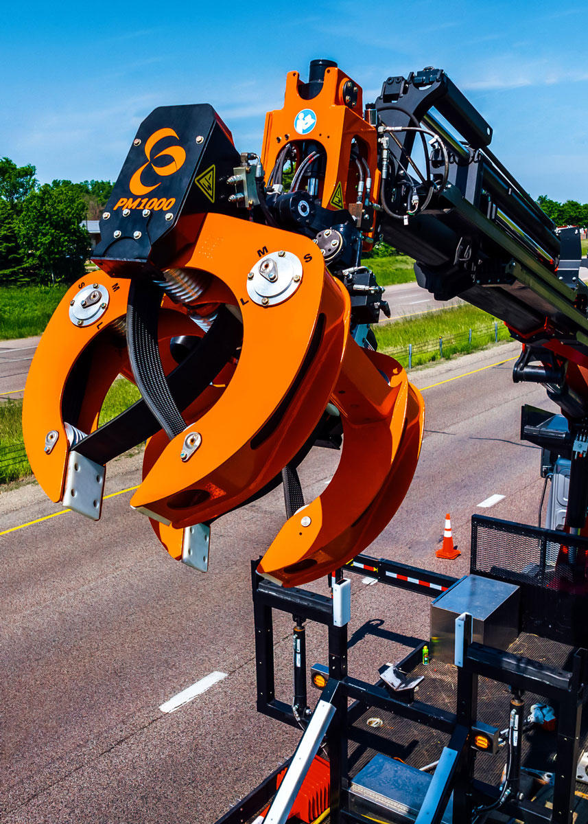 A close-up image of the PM1000™ pole grapple attachment created by LaValley Industries. The PM1000™ is attached to a crane truck and has its grab arms open with drive belts displayed.