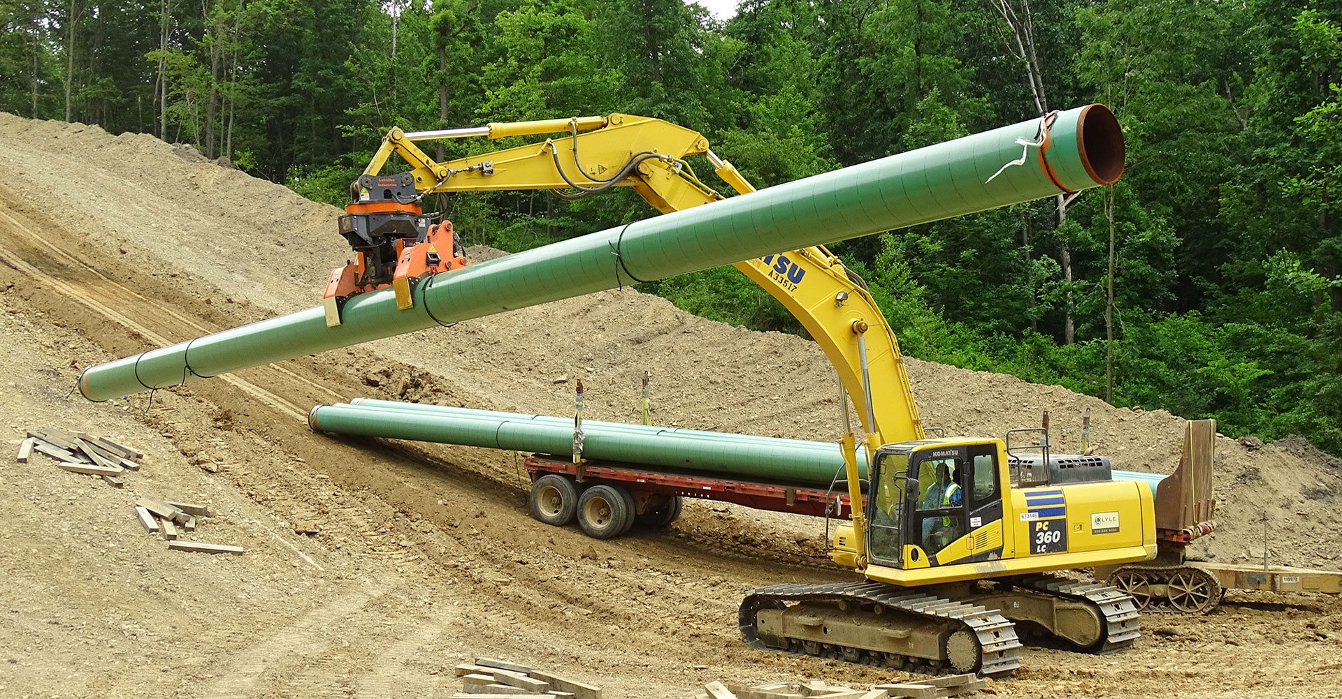 The DECKHAND® system in action! In this image a DECKHAND® is attached to an excavator. Outfitted with Pipe Arms, the DECKHAND® makes quick work of handling pipe around a job site.