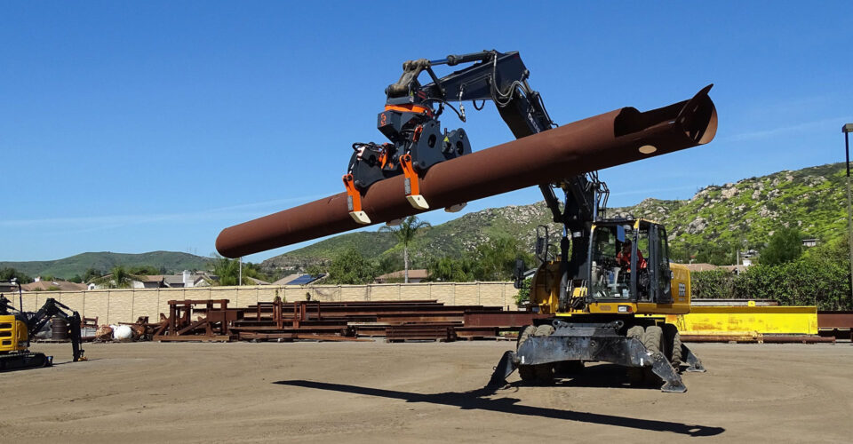 The DECKHAND® system in action! In this image a DECKHAND® is attached to an excavator. Outfitted with Utility Arms, the DECKHAND® makes quick work of horizontal to vertical handling and installing utility poles and casings safely on a civil construction job site.