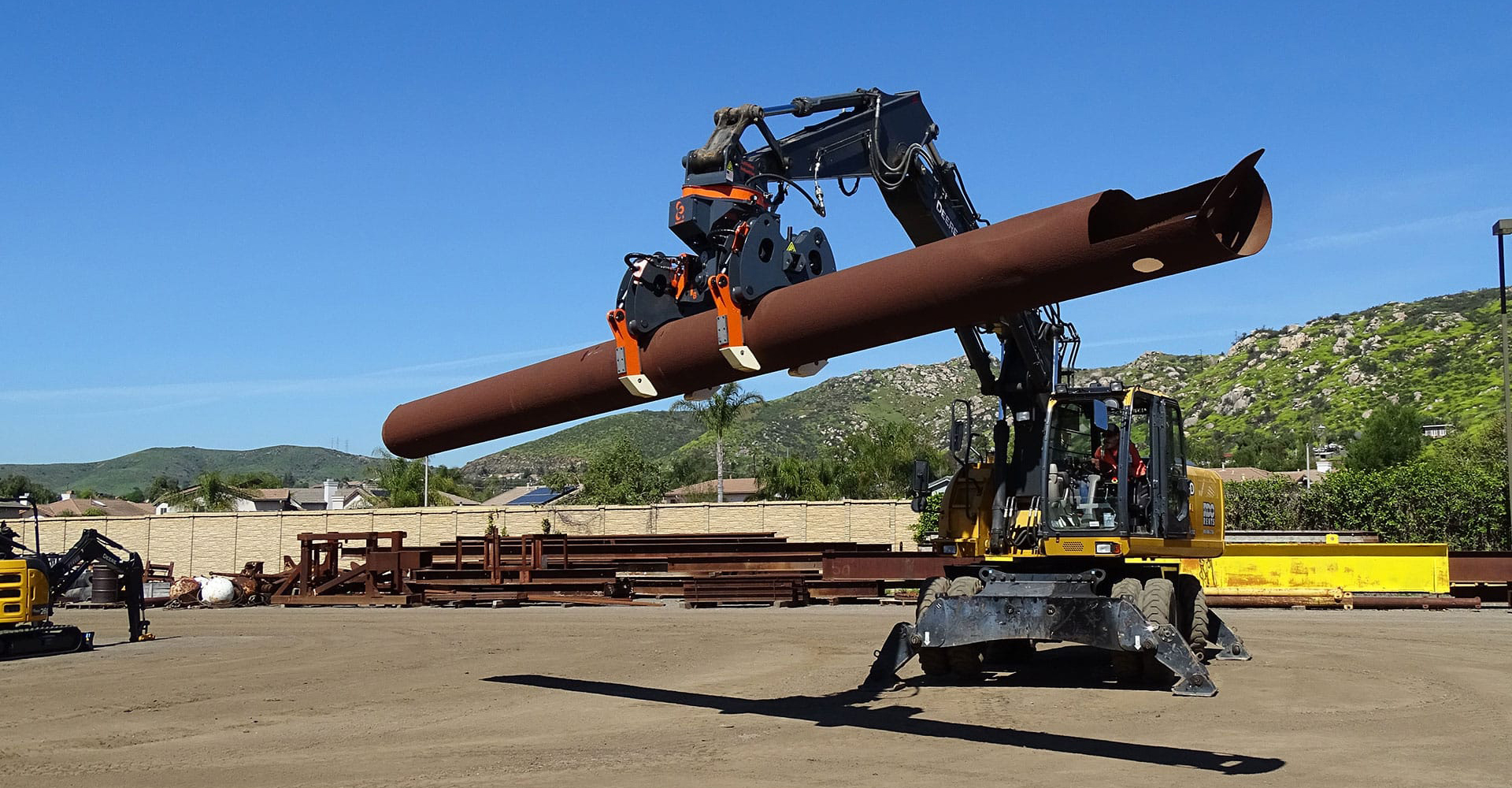 The DECKHAND® system in action! In this image a DECKHAND® is attached to an excavator. Outfitted with Utility Arms, the DECKHAND® makes quick work of horizontal to vertical handling and installing utility poles and casings safely.