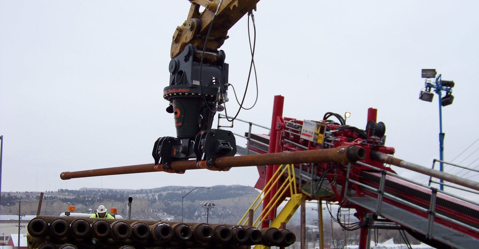 The DECKHAND® system in action! In this image a DECKHAND® is attached to an excavator. Outfitted with Directional Drilling Arms, the DECKHAND® makes quick work of handling drill rod around a job site.