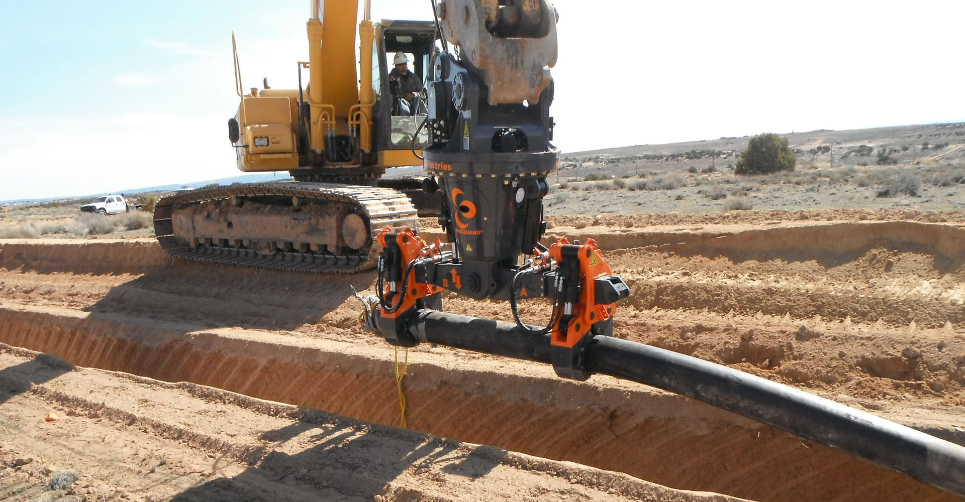 The DECKHAND® system in action! In this image a DECKHAND® is attached to an excavator. Outfitted with Interchangeable Material Handling Arms, the DECKHAND® makes quick work of handling flexible pipe around a job site.